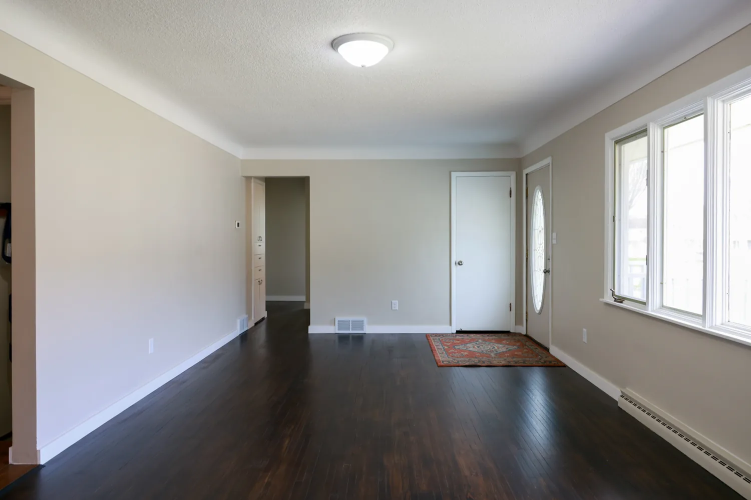 Completed interior wall painting in a bright living room with dark wood floors